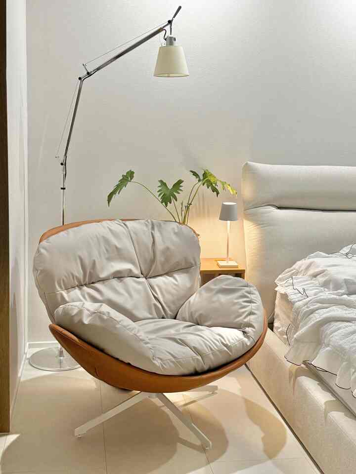 白と茶色のトーンの寝室、快適な1人用アームチェアと照明が配置されたモダンな空間