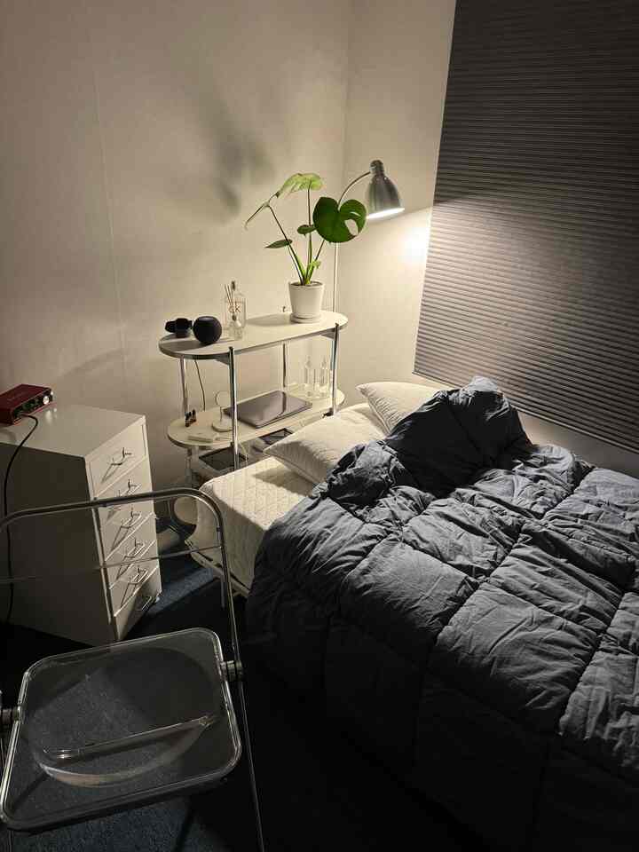 ネイビートーンとホワイトのコンパクトな6坪オフィステル寝室、ベッド、透明チェア、フロアランプと観葉植物が配置されたミッドセンチュリーモダンの印象的な空間