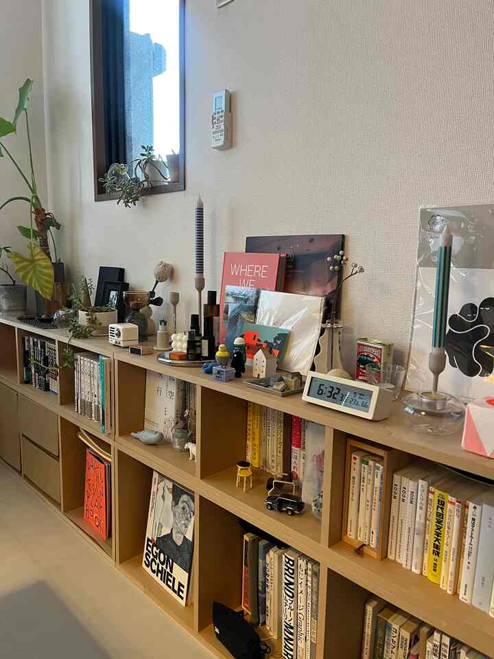 ナチュラルトーンの2LDKリビング、本棚に多彩な小物とキャンドルが配置された印象的な空間