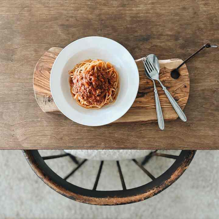 ナチュラルな木目調のキッチンダイニングテーブル、白い皿とカトラリーが配置された温かみのある空間