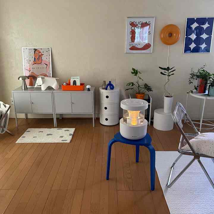 白と茶色のトーンでまとめられた1LDKのリビング、青いスツールの上に加湿器と植物が配置されたモダンで温かみのあるインテリア