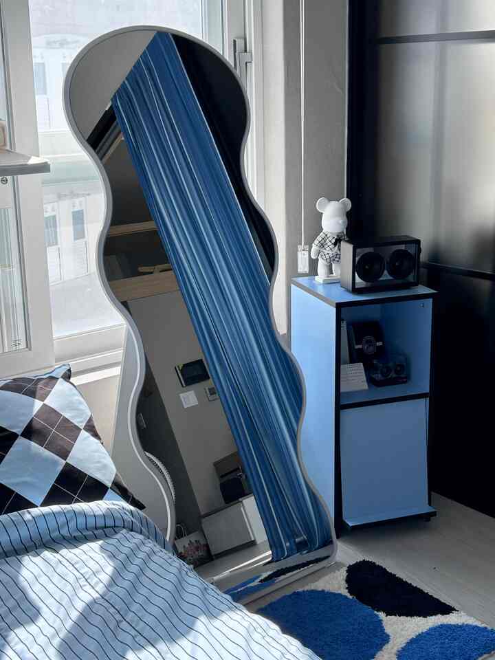 ブルートーンの寝室、曲線形の全身鏡と青い収納キャビネットが配置された印象的なモダンなインテリア