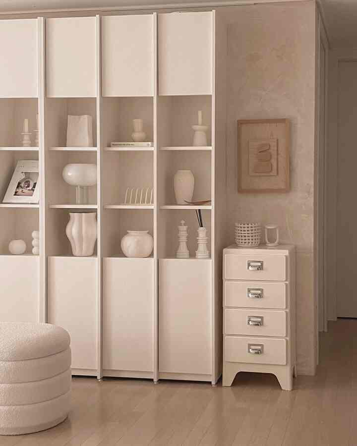 アイボリーとウッドトーンが調和した玄関付近のコンパクトなチェストとナチュラルな壁面が配置された落ち着いた空間