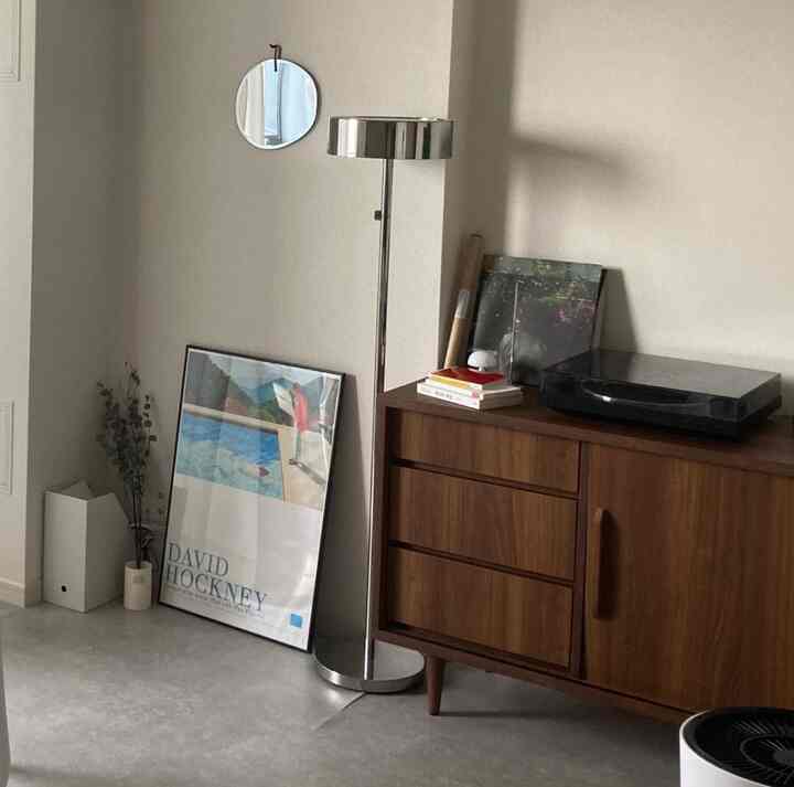 アイボリーの壁と木目調のサイドボードが配置されたモダンでミニマルなリビング空間