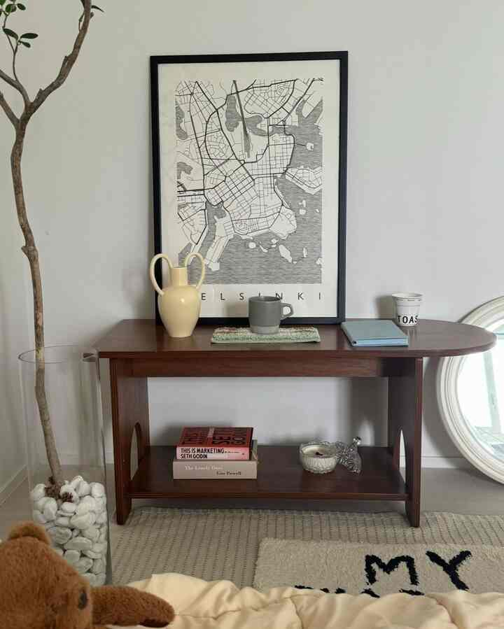 Beige and wood tone living room featuring a wooden console table with framed picture and vase in a simple interior