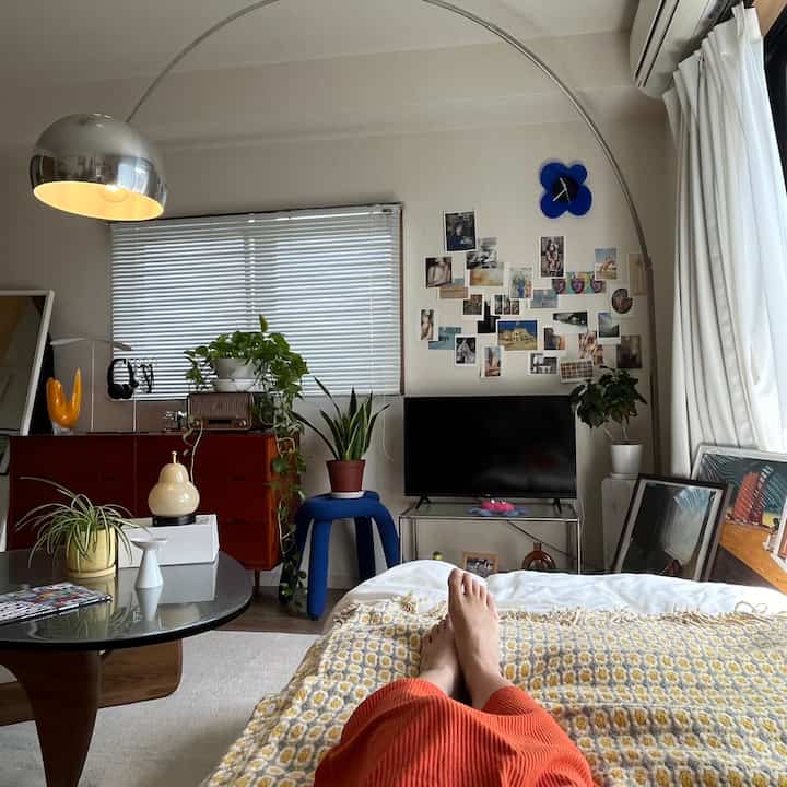 明るいホワイトトーンの8畳リビング、中央左にダークウッドのチェストと多様な植物が配置された雰囲気のあるインテリア