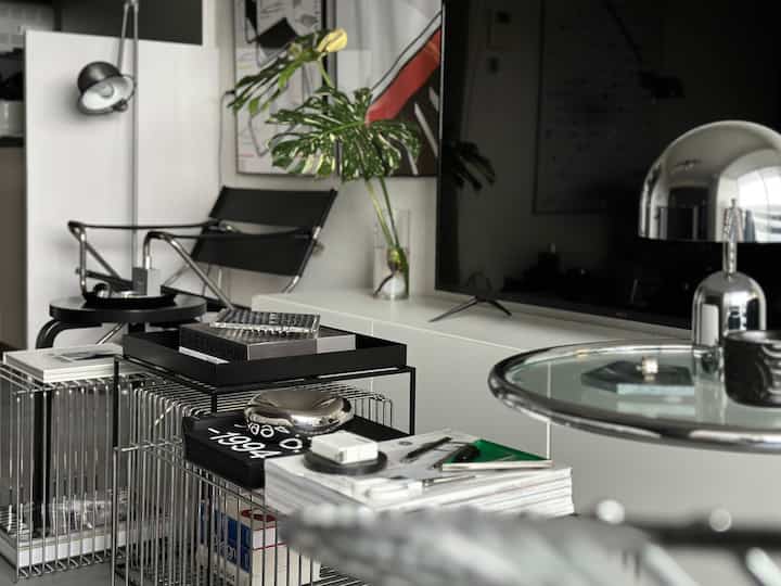 モダンな黒と白のトーンのリビング、スリムなメタルフレームと植物が調和する洗練された空間