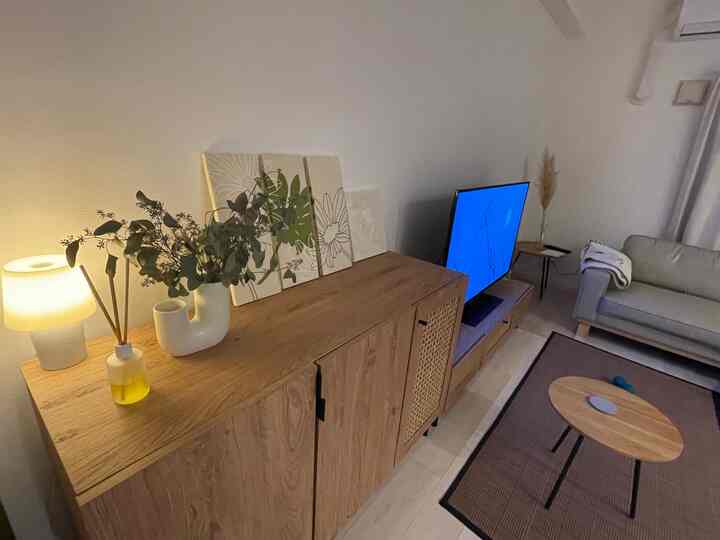 ウッドトーンと温かい照明が調和した北欧スタイルのリビング、キャビネットとソファが配置された落ち着いた空間