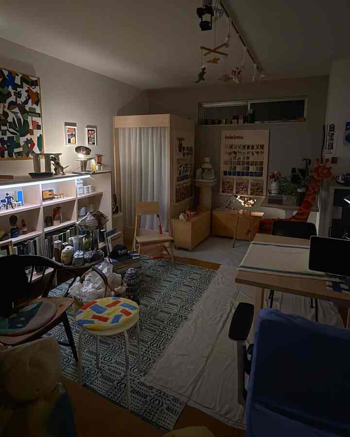 Natural-toned 1LDK studio featuring bookshelves, rugs, various stools, and artistic lighting in a cozy atmosphere