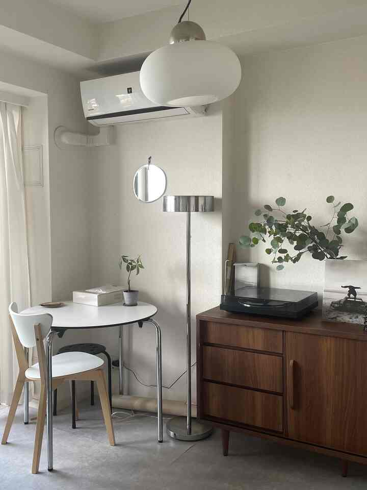 白とシルバーのトーンで統一されたナチュラルモダンなリビング、木製サイドボードと白いダイニングテーブルが配置された清潔感のある空間