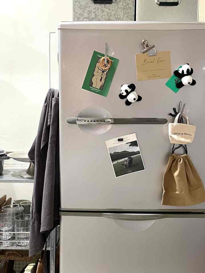 白を基調としたキッチン空間、中央に冷蔵庫が配置され、実用的な収納アイデアや小物がアクセントとなったインテリア