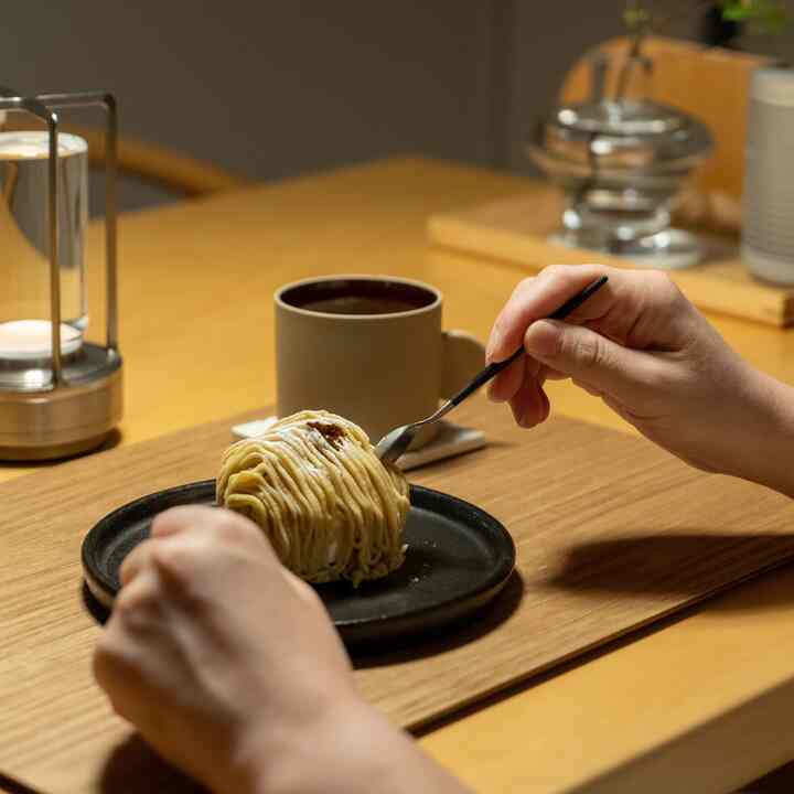 温かみのあるブラウンのホームカフェ空間、木製テーブルにケーキとコーヒーが置かれたシンプルな雰囲気