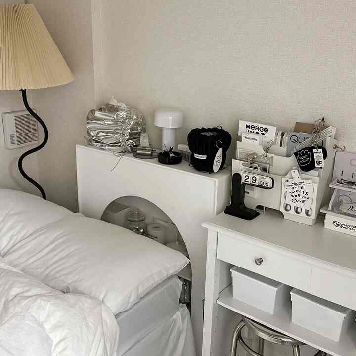 ホワイトトーンの寝室、整った寝具とナイトテーブル、ミニマルなホームオフィスが調和したシンプルなインテリア