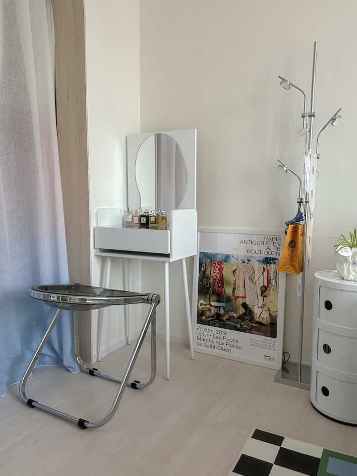 A simple, natural room in white and silver tones, featuring a vanity and stool in a clean layout