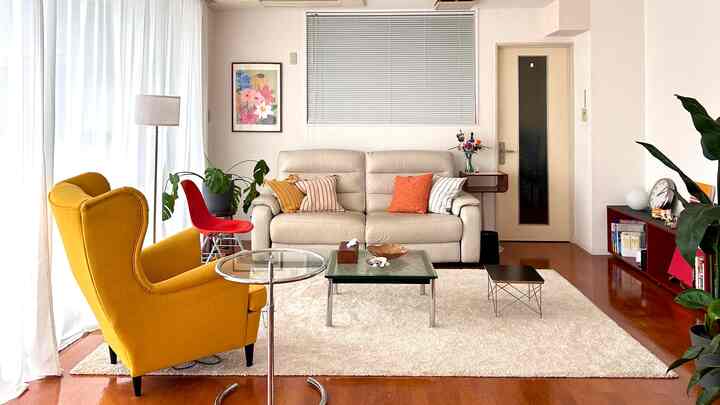 Ivory-toned mid-century modern living room featuring beige sofa, yellow armchair, and red accent pieces with a warm atmosphere