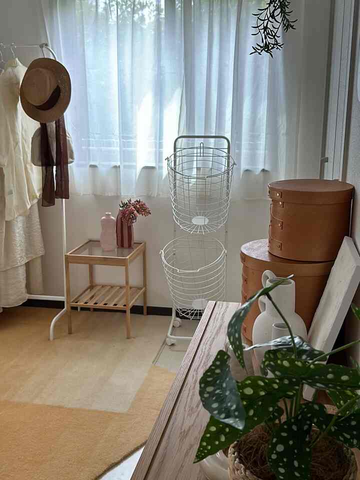 明るい白とあたたかみのある木目調のウォークインクローゼット、白い洋服ラックとシェーカーボックスが配置された清潔で居心地の良い空間