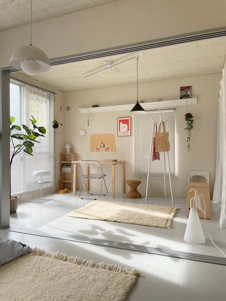 Natural-toned studio apartment home office featuring a wooden desk and transparent chair with a cozy atmosphere