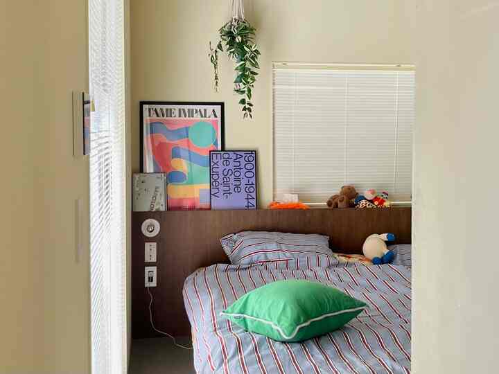 White and brown toned bedroom featuring a bed with striped bedspread and green cushion centered in a simple space