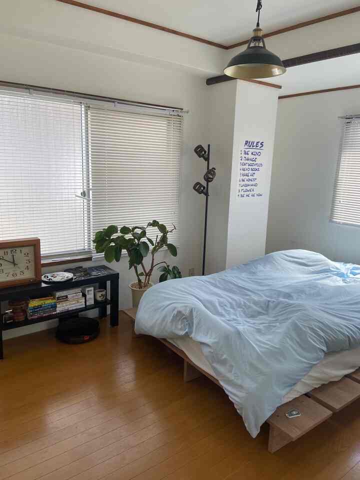 White and brown toned bedroom featuring a wooden bed frame and blinds creating a clean atmosphere