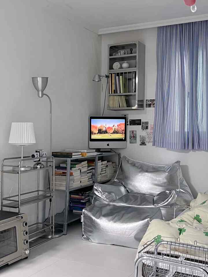 シルバー色調のワンルーム、中央にシルバーのビーズクッションと書棚が配置されたモダンで清潔感のある印象的な空間