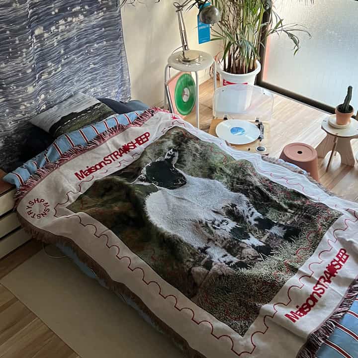 Nordic style bedroom with black and natural toned bed and blanket, plants arranged creating a cozy atmosphere