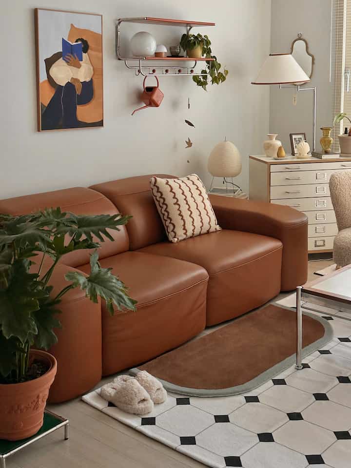 柔らかいブラウンのレザーソファと自然素材の小物が配置されたナチュラルモダンなリビングインテリア