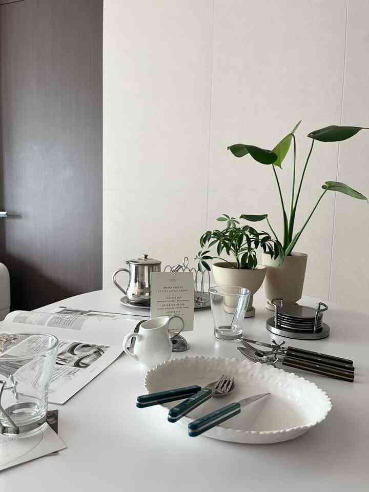 White-toned kitchen space featuring cutlery and plates neatly arranged on a modern dining table