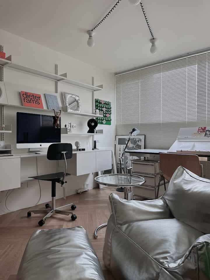 White and silver toned study space featuring mid-century modern desk, shelves, and bean bag chair with a sleek work atmosphere