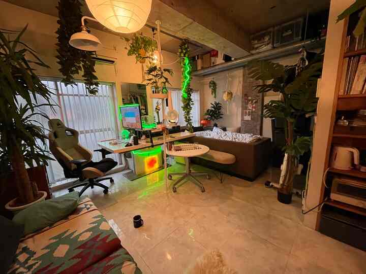 白を基調としたワンルーム、ブラウンのソファとゲーミングデスク、観葉植物とペンダントライトが配されたモダンなインダストリアル空間