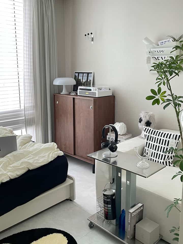 A modern bedroom in white and brown tones featuring a walnut wooden sliding cabinet adding warmth and storage functionality.