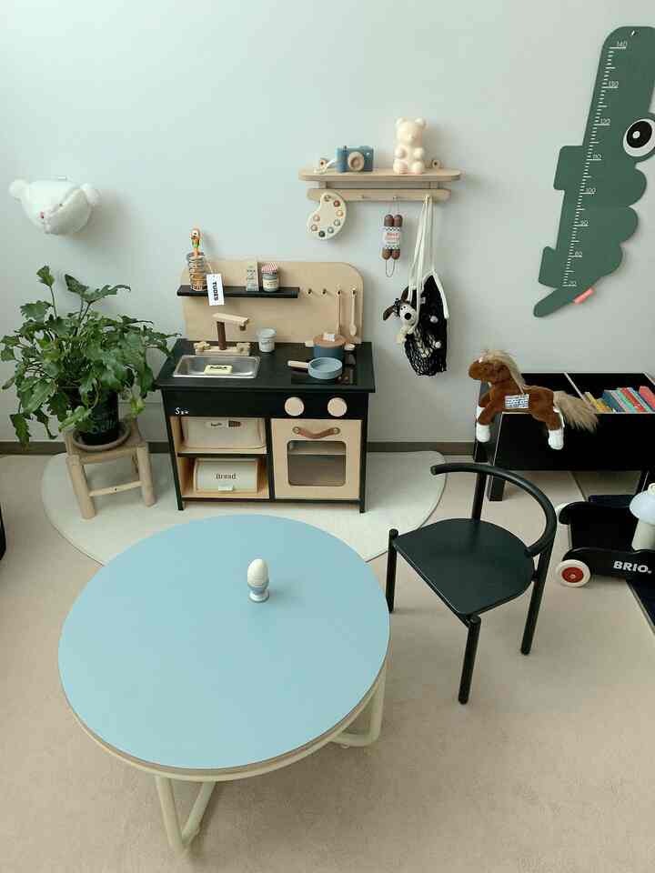 白い壁と黒い家具が配置された子供部屋、ミニマルでナチュラルな植物やおもちゃが調和した印象的な空間