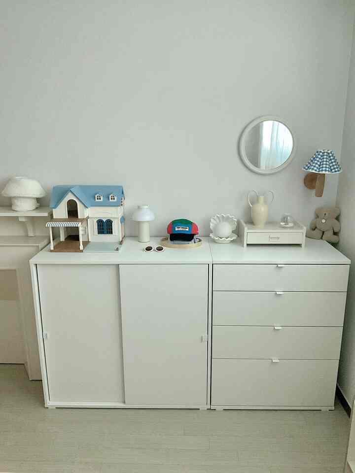 A simple space with white and natural colors featuring tidy storage cabinets and decorative objects