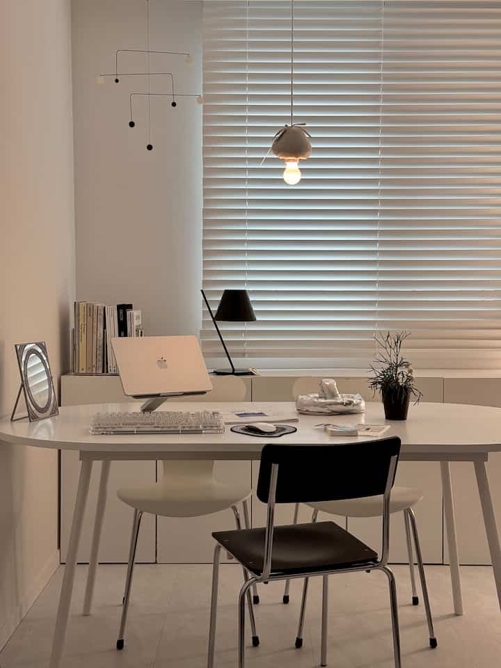 Milky white toned study space featuring a white desk and black chair with clean modern interior design