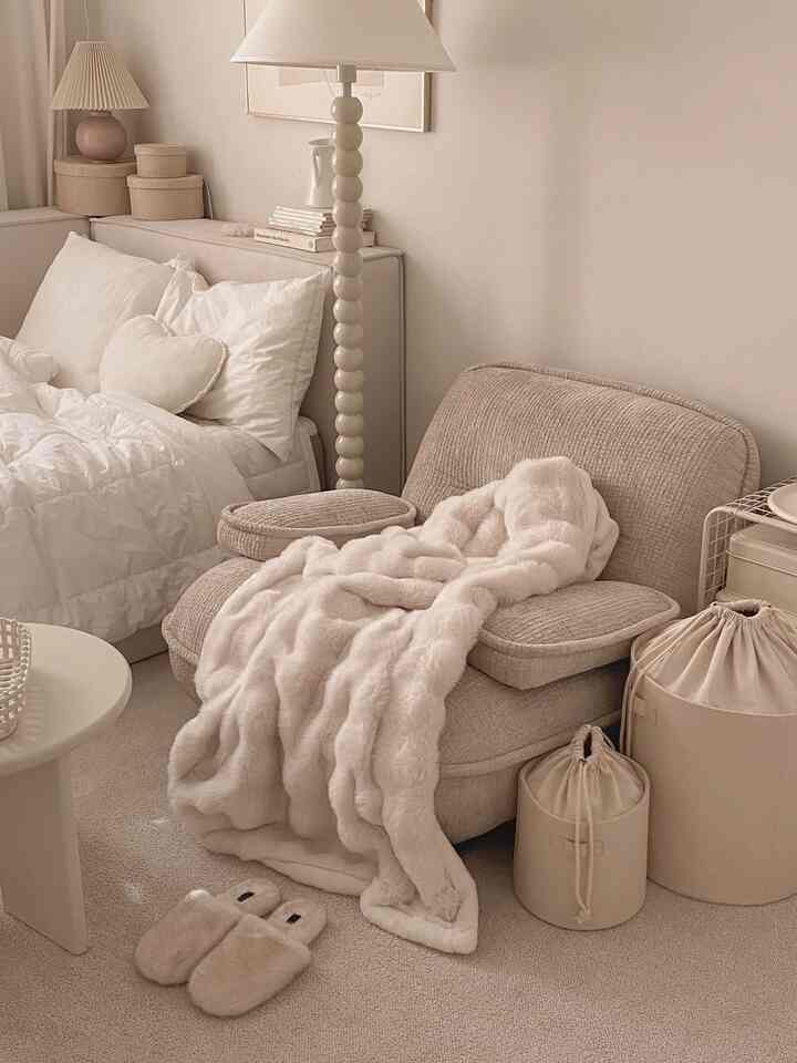 ベージュとホワイトの色調の寝室、ソファとフロアランプ、柔らかなブランケットが配置された雰囲気のあるインテリア