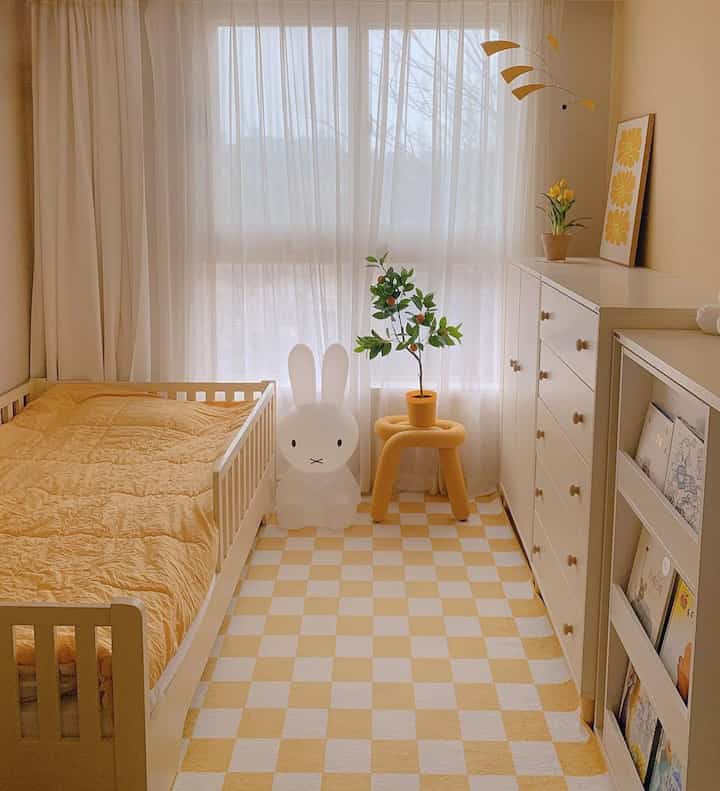 Yellow and white kids' room featuring a child's bed, bookshelf, and plants with a cozy atmosphere