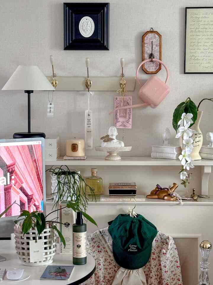 White-toned home office space featuring a desk with plants and table lamp, accented by vintage decor creating a cozy atmosphere