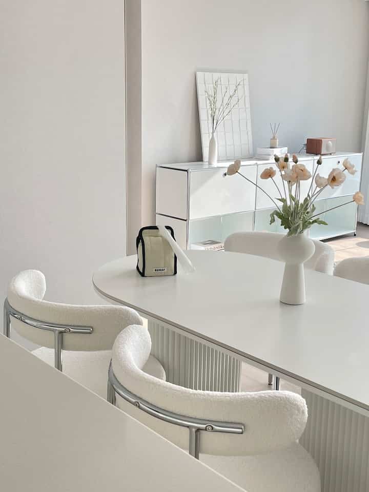White-toned dining room featuring a white dining table and curved chairs with a clean and modern atmosphere