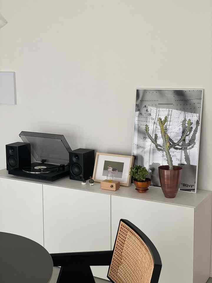 Minimalistic living room with white walls and sideboard, featuring plants, objets d'art, and an armchair