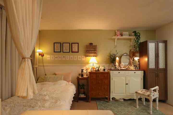 温かみのあるブラウンの木目調とベージュのカーテンが調和する7坪のワンルーム寝室、ヴィンテージ家具と化粧台が配置された雰囲気のあるインテリア