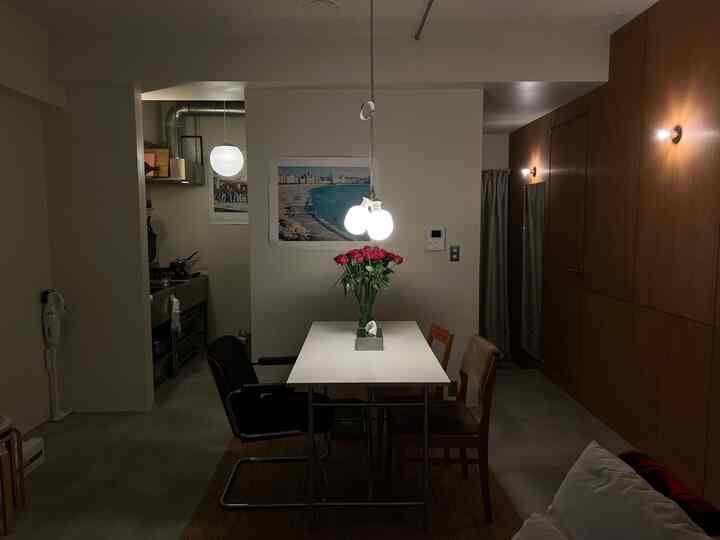 ナチュラルな色調のモダンな2人用リビング兼ダイニングスペース、中央に赤いバラが飾られたテーブルとペンダントライトが配置された印象的な空間