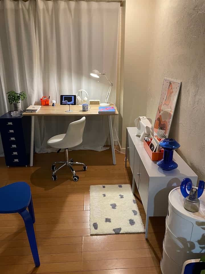 White and blue toned workspace featuring a wooden desk and storage units, creating a modern home office for a two-person household