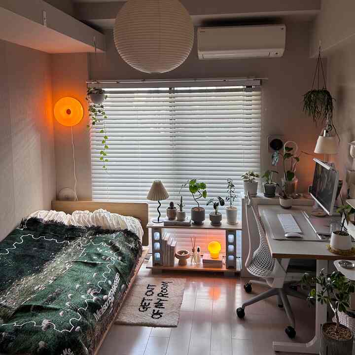 白と木目調が調和した寝室、ベッドとデスク、多数の植物が置かれた雰囲気のあるインテリア