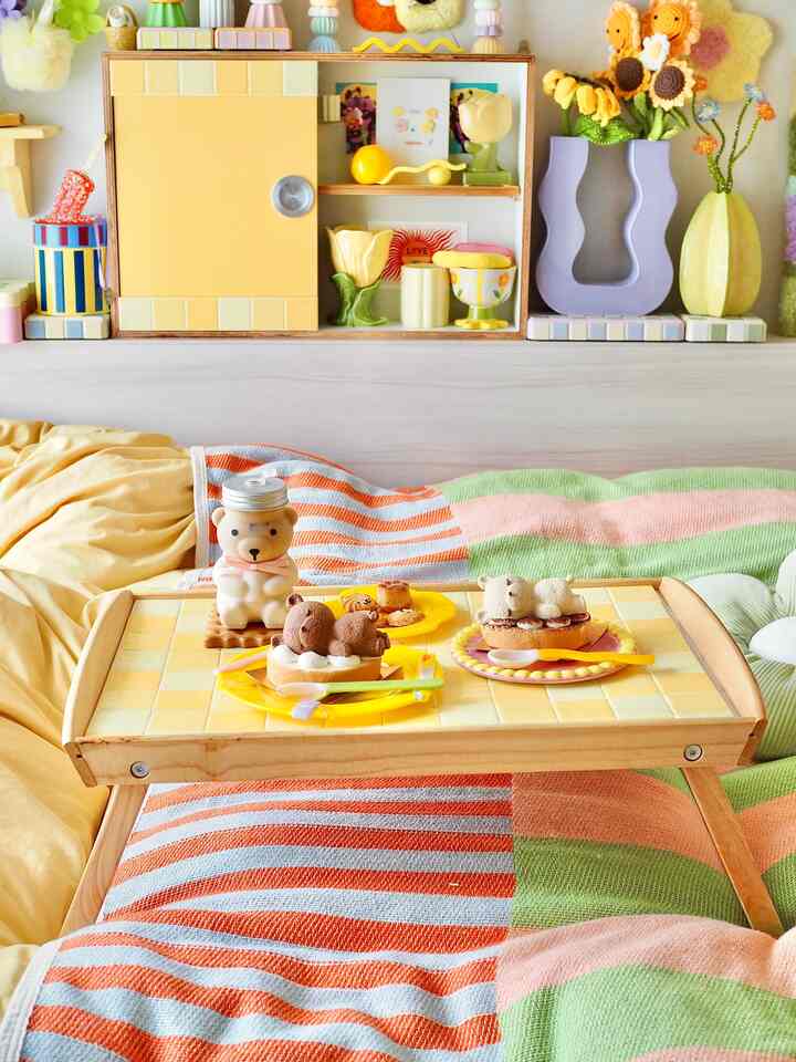 黄色のダイニングルーム、クマの形のケーキとブランケットが配置された温かみのある可愛らしい空間