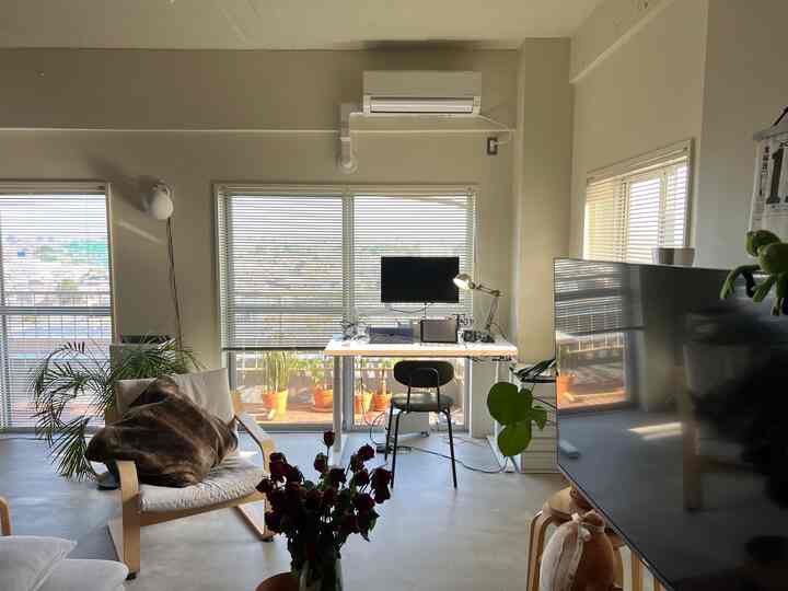 Beige-toned walls and natural wood furniture with large windows, featuring a cozy living room with a home office setup
