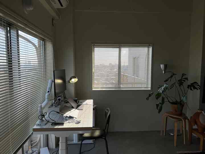 白を基調としたワンルームのホームオフィス、モダンなデスクとオフィスチェア、植物が配置されたシンプルな雰囲気のインテリア