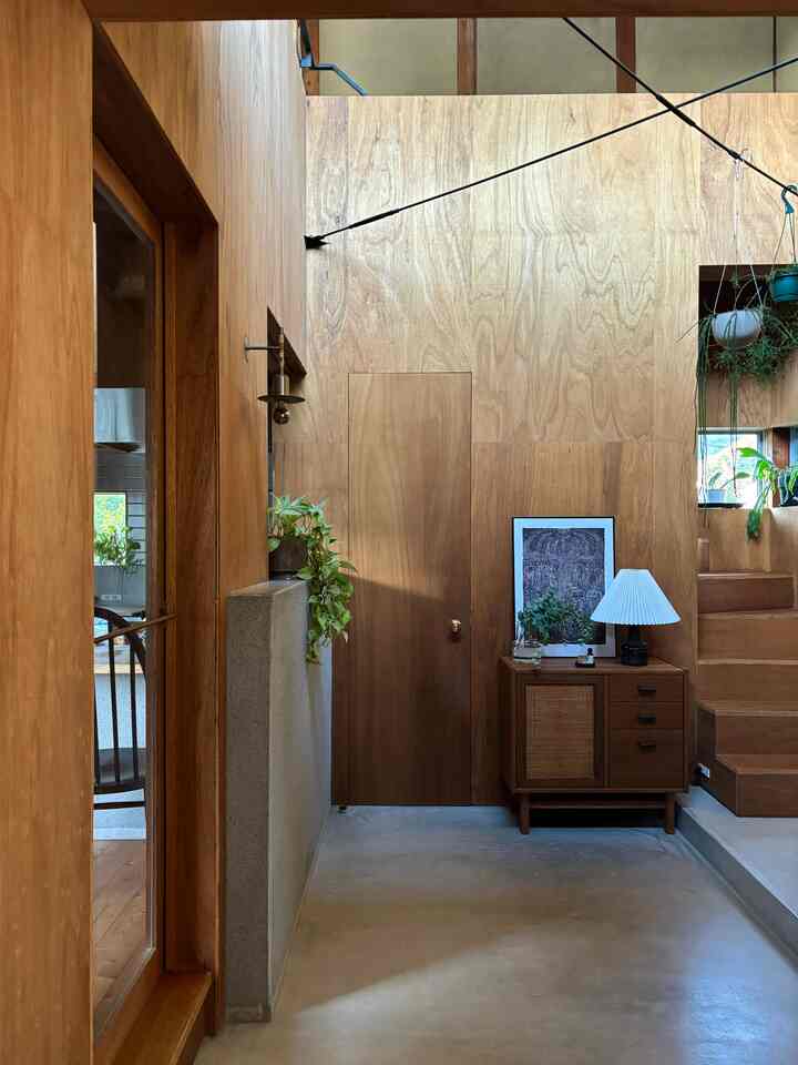 Natural wood tone dominant entrance featuring a cabinet and plants with a warm, modern atmosphere