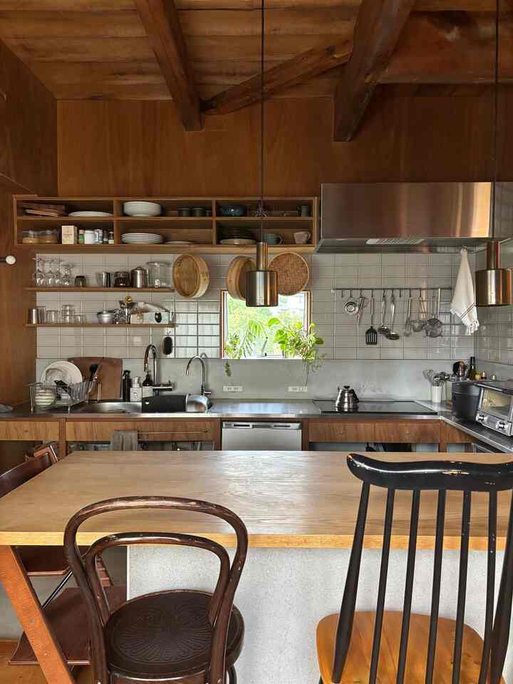 木目調の温かみあるキッチン、木製の椅子とペンダントライトが配置された雰囲気のある空間