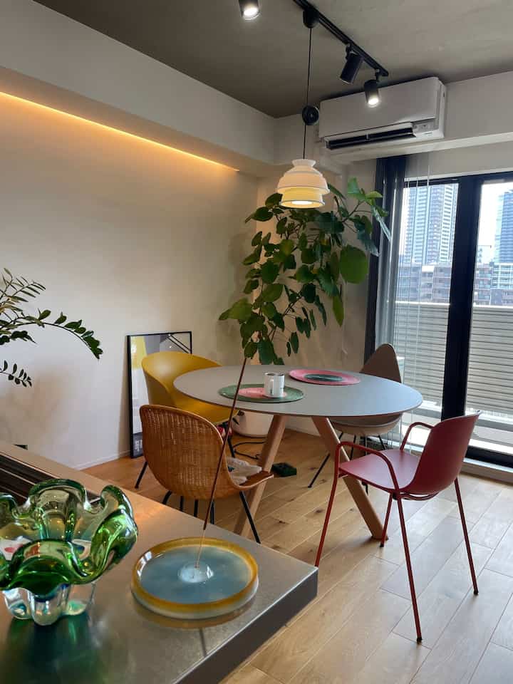 白と木目調の調和が取れたダイニング、丸いダイニングテーブルとカラフルな椅子が配置された落ち着いた印象の空間