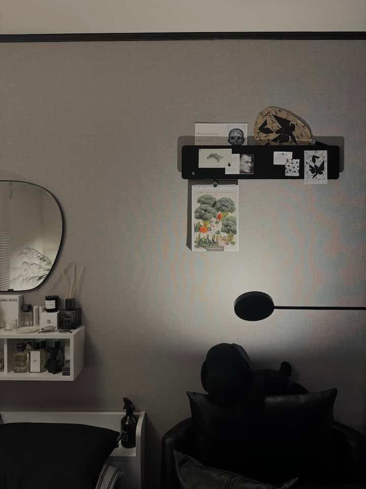 ダークグレーの壁と黒いフロアランプ、ミニマルな壁の装飾が配置されたシンプルな玄関スペース