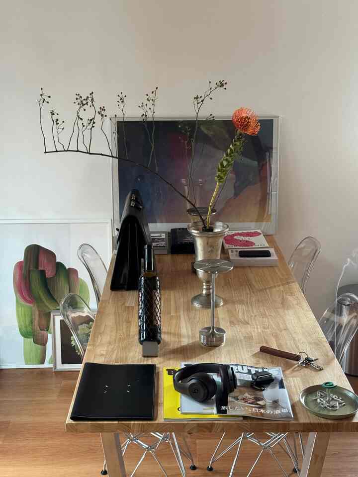 温かみのある木目調の1LDKリビング、透明な椅子と植物が配置されたすっきりとしたウッドテーブルのある印象的な空間